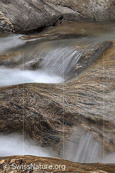 Foto: Langzeitbelichtung von fliessendem Wasser im felsigem Bachbett eines Bergbachs. 
Gestein: Bündnerschiefer.